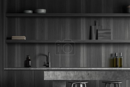 Téléchargez les photos : Intérieur de cuisine sombre avec îlot de bar, deux sièges et évier avec ustensiles de cuisine sur des étagères en bois noir. Zone de cuisson minimaliste dans un appartement moderne. rendu 3D - en image libre de droit