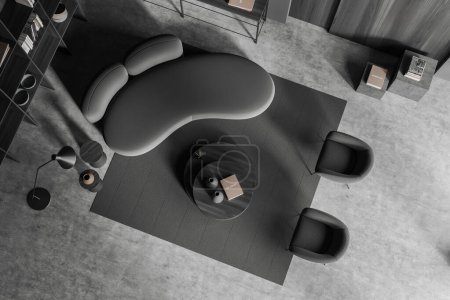 Foto de Vista superior del interior frío oscuro con sofá y dos sillones, estante y mesa de centro con decoración, alfombra en piso de hormigón gris. Renderizado 3D - Imagen libre de derechos