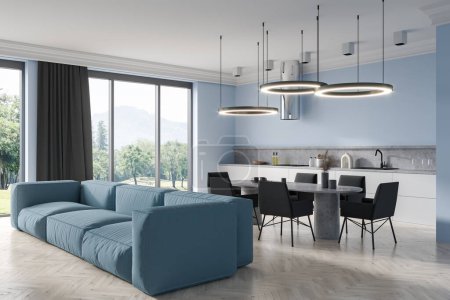 Foto de Estudio interior azul con sofá y mesa de comedor, vista lateral, ventana panorámica al campo. Zona de cocina con electrodomésticos de cocina y espacio frío, suelo de madera blanca. Renderizado 3D - Imagen libre de derechos
