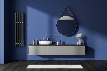 Foto de Interior del baño azul oscuro con lavabo y espejo redondo, cajón y toallero en la pared. Accesorios de baño y alfombra en suelo de madera negra. Renderizado 3D - Imagen libre de derechos