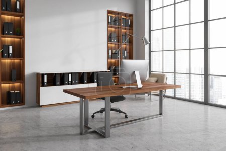 Foto de Interior de la oficina CEO moderna con paredes blancas, piso de hormigón, mesa de madera y armario con carpetas. Ventana con paisaje urbano borroso. Mock up wall. renderizado 3d - Imagen libre de derechos