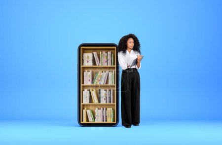 Photo for Black young woman smiling and take note in journal on blue background. Phone with books on shelf. Concept of e-learning and online education. Copy space - Royalty Free Image