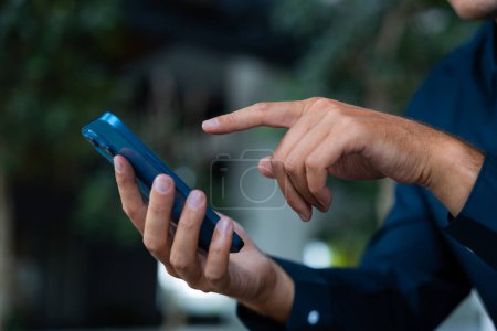 Photo for Man finger point and touch phone closeup, blue shirt and blurred background of green leaves. Concept of online communication, shopping and application - Royalty Free Image