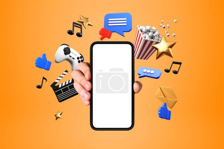 Foto de Mano del hombre mostrando teléfono inteligente con pantalla simulada sobre fondo naranja con iconos de entretenimiento en línea - Imagen libre de derechos