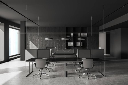 Photo for Interior of stylish open space office with gray and dark wooden walls, concrete floor, rows of computer tables and bookcase with folders. 3d rendering - Royalty Free Image