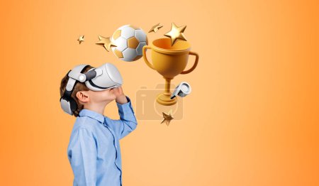 Téléchargez les photos : Enfant garçon jouant à des jeux vidéo en casque VR, divertissement numérique et simulateur. Football, coupe championne et étoile sur fond orange. Concept de réalité virtuelle et gagner - en image libre de droit
