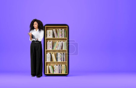 Photo for Black young woman smiling and take note in journal on purple background. Smartphone with books on shelf. Concept of digital library. Copy space - Royalty Free Image
