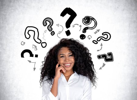 Photo for Black businesswoman with dreaming and happy look. Doodle question marks on grey concrete background. Concept of career development and education - Royalty Free Image