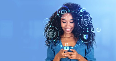 Photo for Portrait of smiling young African American woman using smartphone with immersive biometric scanning interface over blue background. Mock up - Royalty Free Image