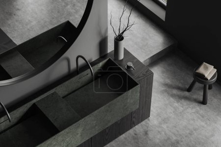Foto de Vista superior del interior del baño oscuro con lavabo y grifos dobles, espejo redondo y taburete con accesorios de baño en piso de hormigón gris. Renderizado 3D - Imagen libre de derechos