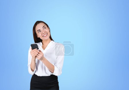 Photo for Smiling businesswoman working with phone, online browse internet and thinking on blue background. Concept of communication and social media. Copy space - Royalty Free Image