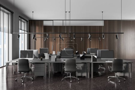 Téléchargez les photos : Intérieur du bureau moderne à aire ouverte avec des murs en bois gris et foncé, sol en pierre et rangées de tables d'ordinateur grises avec des chaises. Rendu 3d - en image libre de droit