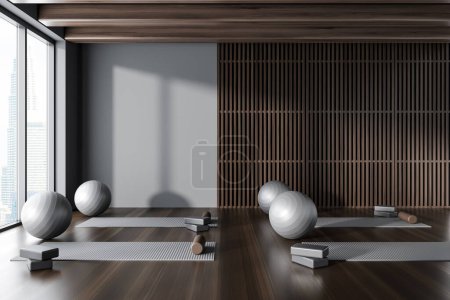 Foto de Interior de un moderno estudio de yoga con paredes de madera gris y oscura, suelo de madera oscura, colchonetas de yoga y pelotas grises. renderizado 3d - Imagen libre de derechos