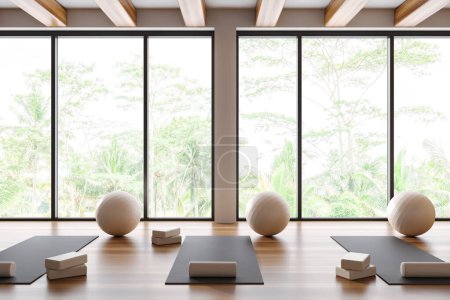 Foto de Interior de gimnasio de yoga de madera con estera y fitball con bloque y rodillo, piso de madera dura. Sala de clases de fitness con equipo y ventana panorámica en los trópicos. Renderizado 3D - Imagen libre de derechos