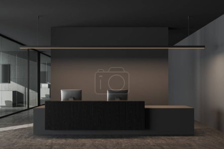 Photo for Dark office room interior with reception desk and pc computers, business hallway in company and grey concrete floor. Meeting and coworking space behind glass doors. 3D rendering - Royalty Free Image