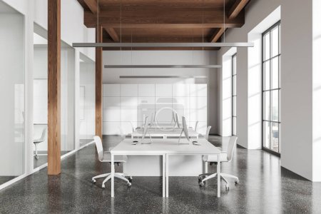 Foto de Moderno interior de coworking con sillones y ordenador PC en el escritorio en fila, piso de hormigón gris. Oficina blanca y ventana panorámica en rascacielos. Renderizado 3D - Imagen libre de derechos