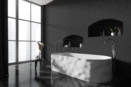 Foto de Interior de baño oscuro con bañera, vista lateral, accesorios de baño en piso de baldosas negras. Zona de baño en el estudio del hotel con ventana panorámica a Singapur. Renderizado 3D - Imagen libre de derechos