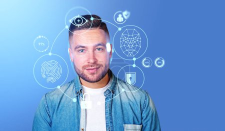 Photo for Portrait of bearded young man in casual clothes using immersive facial recognition interface over blue background. Concept of biometric scanning. Mock up - Royalty Free Image
