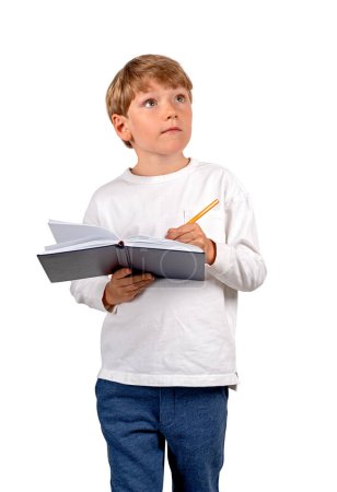Foto de Niño soñador con bolígrafo tomando notas en cuaderno, retrato inspirado mirando hacia arriba aislado sobre fondo blanco. Concepto de educación, investigación y estudios en línea - Imagen libre de derechos