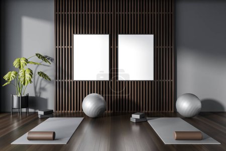 Photo for Interior of modern yoga studio with gray and dark wooden walls, dark wooden floor, yoga mats and gray fitballs. Two vertical mock up posters. 3d rendering - Royalty Free Image