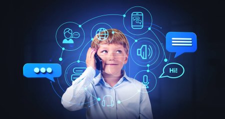 Foto de Niño sonriente hablando por teléfono, chat holograma bot con burbujas de voz e iconos de comunicación. Asistente virtual y servicios en línea. Concepto de inteligencia artificial y tecnología - Imagen libre de derechos