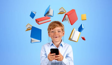 Téléchargez les photos : Portrait d'écolier souriant avec smartphone dans les mains, volant des icônes de livres colorés sur fond bleu. Concept d'apprentissage en ligne, d'éducation, de bibliothèque numérique et d'application mobile - en image libre de droit