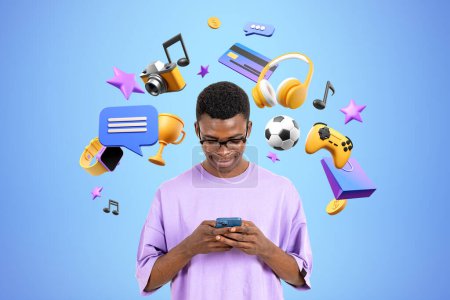 Foto de Hombre negro sonriente jugar videojuegos, escribiendo en el teléfono, diversos iconos del mundo digital sobre fondo azul. Concepto de medios sociales, entretenimiento y compras en línea - Imagen libre de derechos