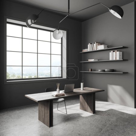 Photo for Dark home office interior with laptop computer on desk, side view minimalist shelf with decoration and grey concrete floor. Panoramic window on countryside. 3D rendering - Royalty Free Image