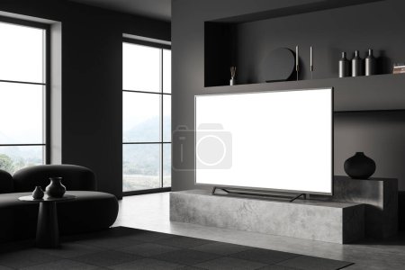 Photo for Dark lounge interior with sofa and tv on a concrete stand, side view, chill space with shelf and art decoration. Panoramic window on countryside. Mock up blank tv display. 3D rendering - Royalty Free Image