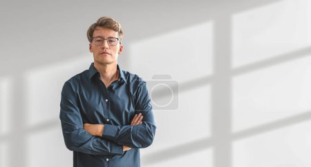Photo for Serious businessman in blue shirt, looking at the camera, arms crossed on empty copy space white shadow background. Concept of business plan, idea and development - Royalty Free Image