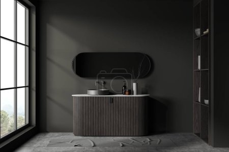 Téléchargez les photos : Intérieur de la salle de bain élégante avec des murs gris foncé, sol en béton, lavabo rond confortable debout sur armoire en bois sombre et miroir ovale. Rendu 3d - en image libre de droit