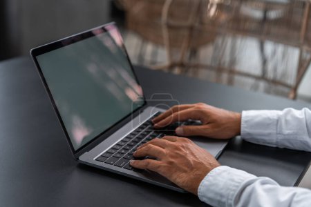Foto de Vista lateral del hombre que trabaja en el ordenador portátil en la mesa, dedos escribiendo en el teclado. Simular pantalla de espacio de copia. Concepto de compras en línea, anuncio, promoción y sitio web - Imagen libre de derechos