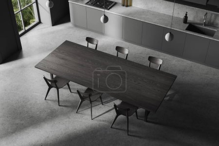Photo for Top view of dark kitchen interior with black wooden dining table and chairs, grey concrete floor. Hotel cooking corner with kitchenware. Panoramic window on tropics. 3D rendering - Royalty Free Image
