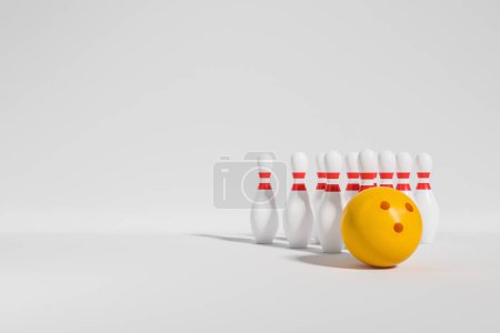 Foto de Bola de bolos amarilla y diez alfileres sobre fondo blanco. Concepto de deporte y actividad. Copiar espacio. Renderizado 3D - Imagen libre de derechos