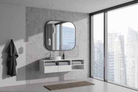 Foto de Elegante baño interior con lavabo y espejo, vista lateral, accesorios de baño y toalla de pie en el suelo de hormigón gris. Ventana panorámica de los rascacielos de Singapur. Renderizado 3D - Imagen libre de derechos