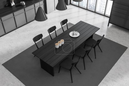 Téléchargez les photos : Vue de dessus de l'intérieur de la cuisine sombre avec table à manger et chaises, tapis sur sol en béton gris. Fenêtre panoramique sur vue sur la ville. Coin repas avec mobilier moderne. rendu 3D - en image libre de droit