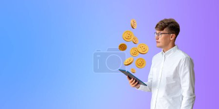 Foto de Retrato de un joven empresario europeo concentrado en camisa blanca sosteniendo una tableta de pie cerca de la pared púrpura con bitcoins sobre él. Concepto de criptomoneda, DEX, DeFi. Copiar espacio - Imagen libre de derechos