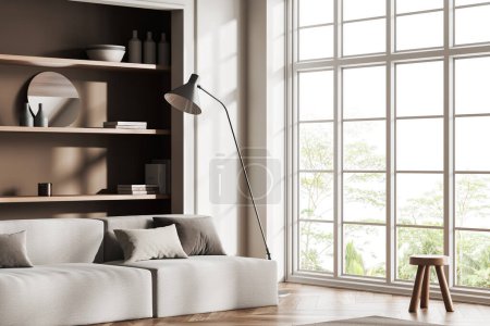 Foto de Interior de la sala de estar beige con sofá y taburete, vista lateral, suelo de madera. Rincón frío con estante loft y decoración de arte, ventana panorámica en los trópicos. Renderizado 3D - Imagen libre de derechos