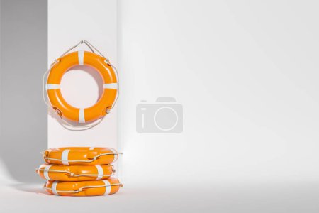 Photo for Orange lifebuoys hanging on white wall, stack of life saving rings. Concept of rescue and beach. Copy space - Royalty Free Image