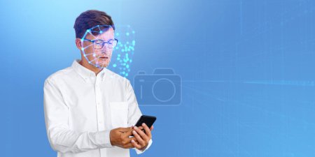 Photo for Serious young European businessman in white shirt using smartphone with immersive facial recognition interface standing over blue background. Concept of biometric scanning. Copy space - Royalty Free Image