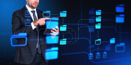Photo for Unrecognizable businessman using tablet computer over dark blue background with double exposure of immersive DMS document management system interface. Concept of data management - Royalty Free Image
