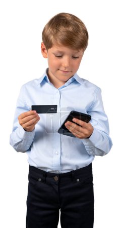 Téléchargez les photos : Portrait d'adorable petit garçon en vêtements formels tenant smartphone et carte de crédit isolé sur fond blanc. Concept de banque en ligne et d'achats en ligne - en image libre de droit
