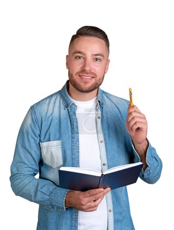 Téléchargez les photos : Portrait d'un étudiant souriant barbu dans des vêtements décontractés tenant un cahier et un stylo isolés sur fond blanc. Concept d'éducation et de brainstorming - en image libre de droit