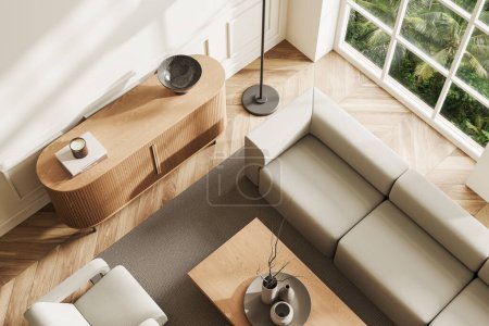 Téléchargez les photos : Vue de dessus du salon moderne avec des murs blancs, sol en bois, confortable canapé gris et fauteuil debout près de la table basse et commode en bois. Rendu 3d - en image libre de droit