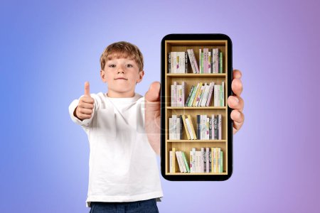 Photo for Handsome boy in casual wear is showing smartphone case with digital library with approval. Bookshelf with various books. Concept of e-learning and online education. Gradient purple wall in background - Royalty Free Image
