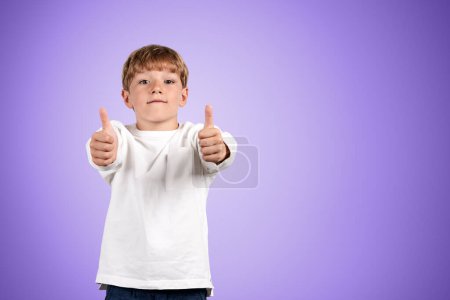 Photo for Child boy looking at the camera and showing thumbs up, copy space empty purple background. Concept of recommendation and like - Royalty Free Image