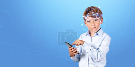 Téléchargez les photos : Téléphone tactile de garçon de l'école à la main, hologramme de vérification biométrique et reconnaissance faciale sur fond de matrice d'espace de copie. Concept d'identité faciale, de sécurité sur Internet et de contrôle parental - en image libre de droit