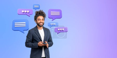 Photo for Smiling Middle Eastern businessman holding smartphone, text message bubbles over purple background. Concept of social media, business conversation and online network - Royalty Free Image