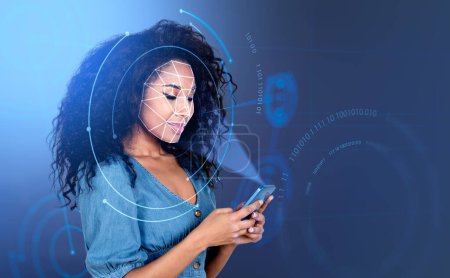 Photo for Smiling attractive African American businesswoman wearing formal wear is trying to unlock her smartphone. Circle hologram with binary code. Concept of facial recognition, biometric scanning - Royalty Free Image