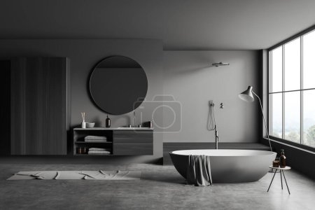 Téléchargez les photos : Intérieur sombre salle de bain avec lavabo et douche sur podium, baignoire près de la fenêtre panoramique sur la campagne. Commode avec accessoires de bain, sol en béton gris. rendu 3D - en image libre de droit